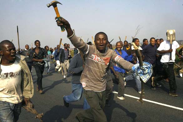 A South African mob runs on the main road near the Reiger Park informal settlement outside Johannesburg, South Africa, Tuesday, May 20, 2008. Clashes pitting the poorest of the poor against one another have focused attention on complaints that South Africa's post-apartheid government has failed to deliver enough jobs, housing and schools to go around. (AP Photo/Jerome Delay)